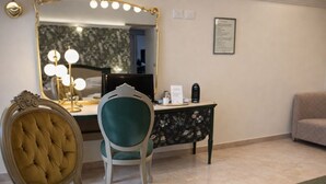 Une pièce comprenant une coiffeuse, une chaise, un bureau avec un ordinateur et un canapé.