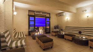 Ein Sitzbereich mit Rattanmöbeln, einem Fernseher und Blick auf die Stadt durch ein großes Fenster.