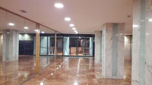 Un vestíbulo espacioso con suelo de mármol, paredes de cristal y una escalera que conduce a un nivel superior.