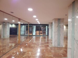 Eine geräumige Lobby mit Marmorböden, Glaswänden und einer Treppe zu einer oberen Ebene.
