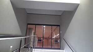 Una escalera conduce a una habitación con un ventanal grande, un letrero arriba que dice 'FLYPALACE' y una barandilla de metal a la izquierda.