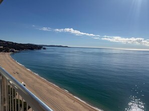 Eine Küstenansicht mit Strand, blauem Himmel und Bergen in der Ferne.