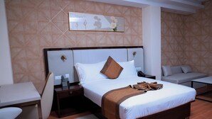 Camera d'albergo con un letto grande, un comodino, una sedia, una scrivania e un'opera d'arte appesa al muro.