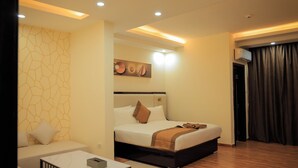 Una camera d'albergo con un letto, un divano, un quadro e una lampada a soffitto.