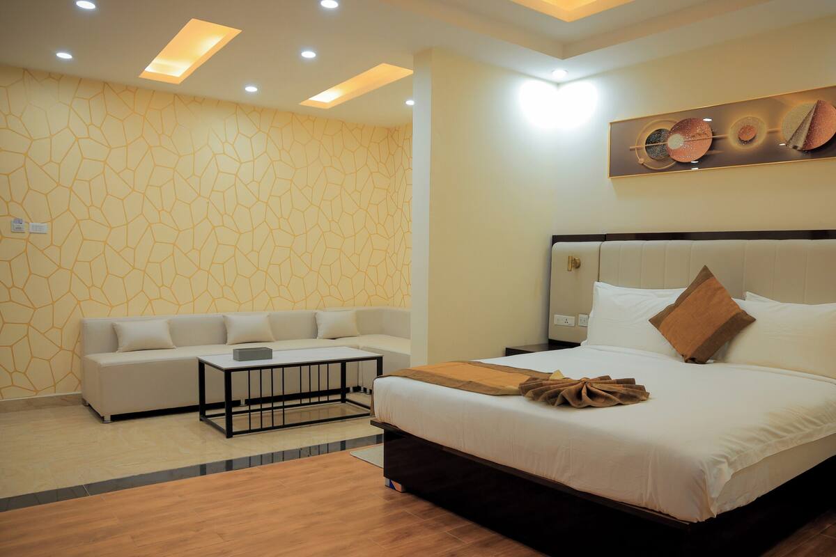 A hotel room with a bed, a sofa, a coffee table, and a wall art piece.