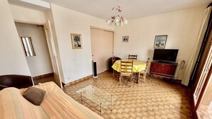 Een woonkamer met een bank, een eettafel met stoelen, een televisie en een open haard.