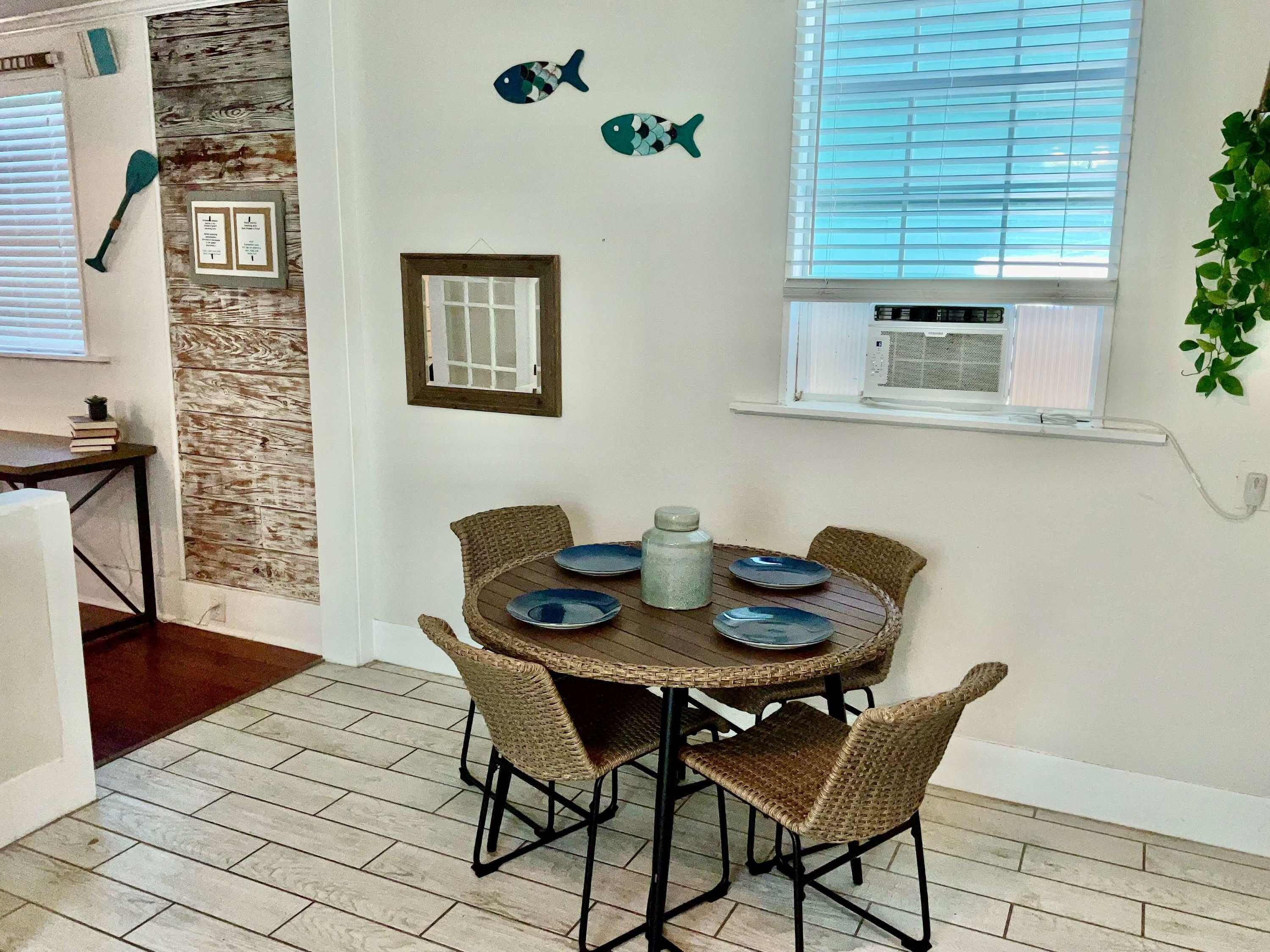 A dining area with a round table, wicker chairs, and blue plates.