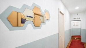 A hallway with a geometric wall art installation, a 'WELCOME' sign, and a red carpet leading to a door. - Hotiday La Spezia Quiet Night (La Spezia)