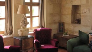 Une pièce avec un fauteuil rouge, un canapé vert, une lampe et une petite table sur laquelle se trouve un cadre photo.