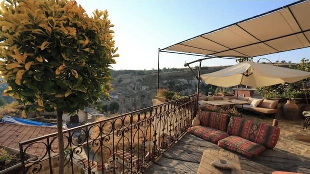 Une terrasse avec un ensemble de canapés, une table et un grand parasol.