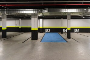 En parkeringskælder med nummererede parkeringspladser og et område med blå tæppe.