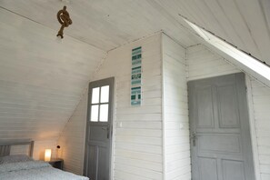 Une pièce avec un plafond en pente, un lit, une table de chevet avec une lampe et un mur décoré sur le thème de la marine.