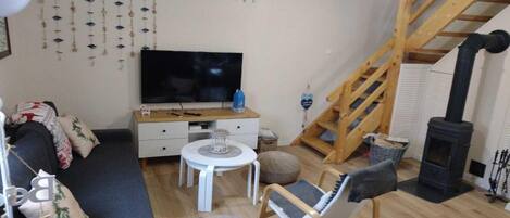 A cozy living room with a sofa, a TV, a small table, and a wooden staircase.
