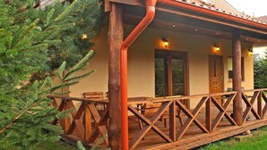 A wooden cabin with a porch, a wooden deck, and a window overlooking a forested area. - Year-round Holiday Home With Fireplace, 3 Bedrooms (Choczewo)