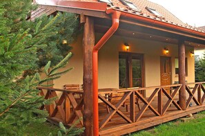 A wooden cabin with a porch, a wooden deck, and a window overlooking a forested area. - Year-round Holiday Home With Fireplace, 3 Bedrooms (Choczewo)