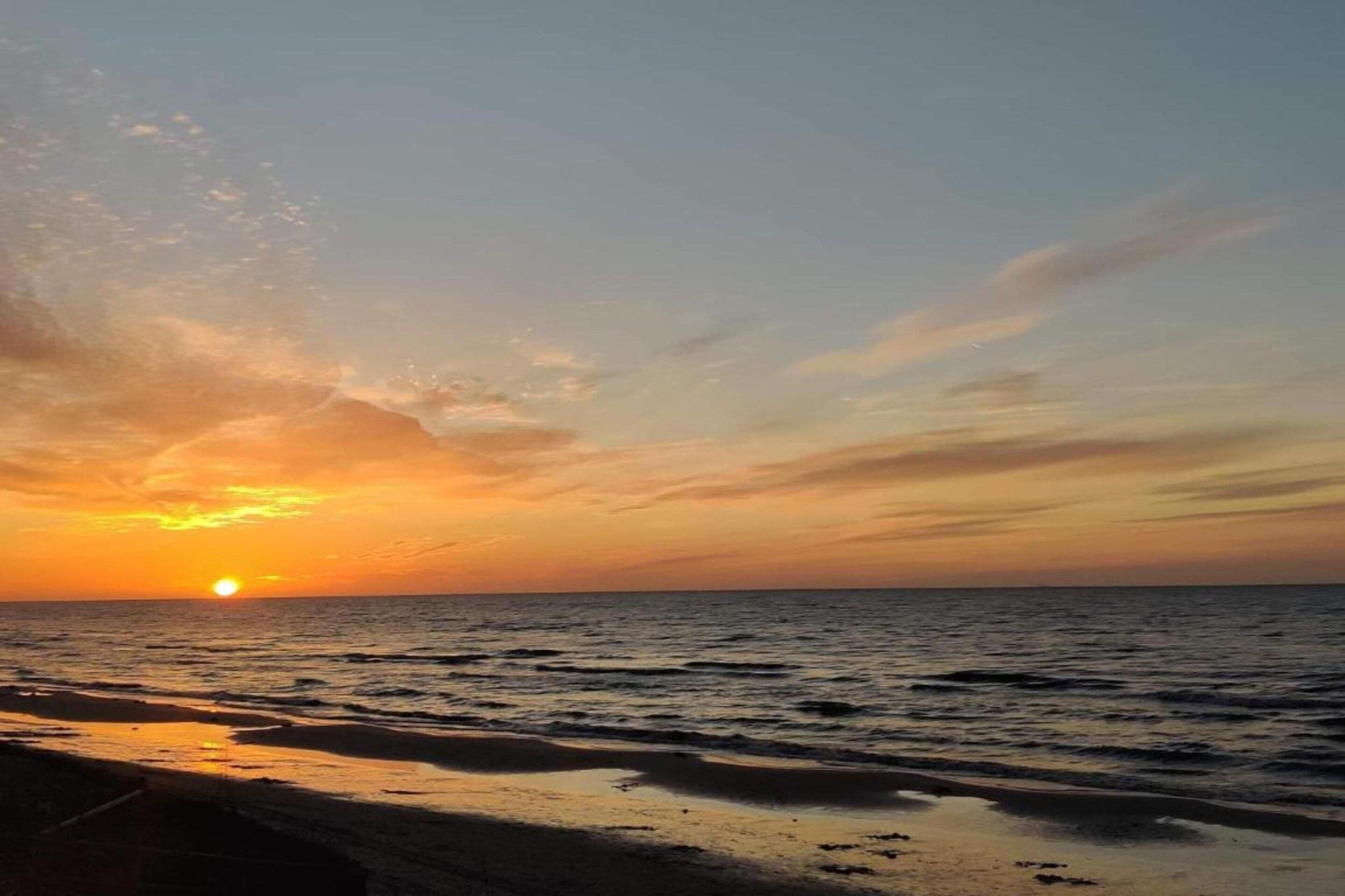Un atardecer sobre un mar tranquilo con un horizonte despejado.