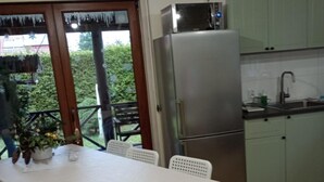 A kitchen with a stainless steel refrigerator, a sink, and a dining area with a table and chairs. - Year-round Holiday Home With Fireplace, 3 Bedrooms (Choczewo)