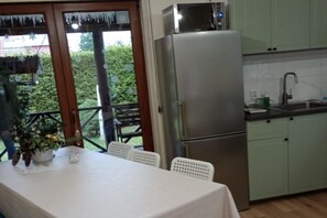A kitchen with a stainless steel refrigerator, a sink, and a dining area with a table and chairs. - Year-round Holiday Home With Fireplace, 3 Bedrooms (Choczewo)