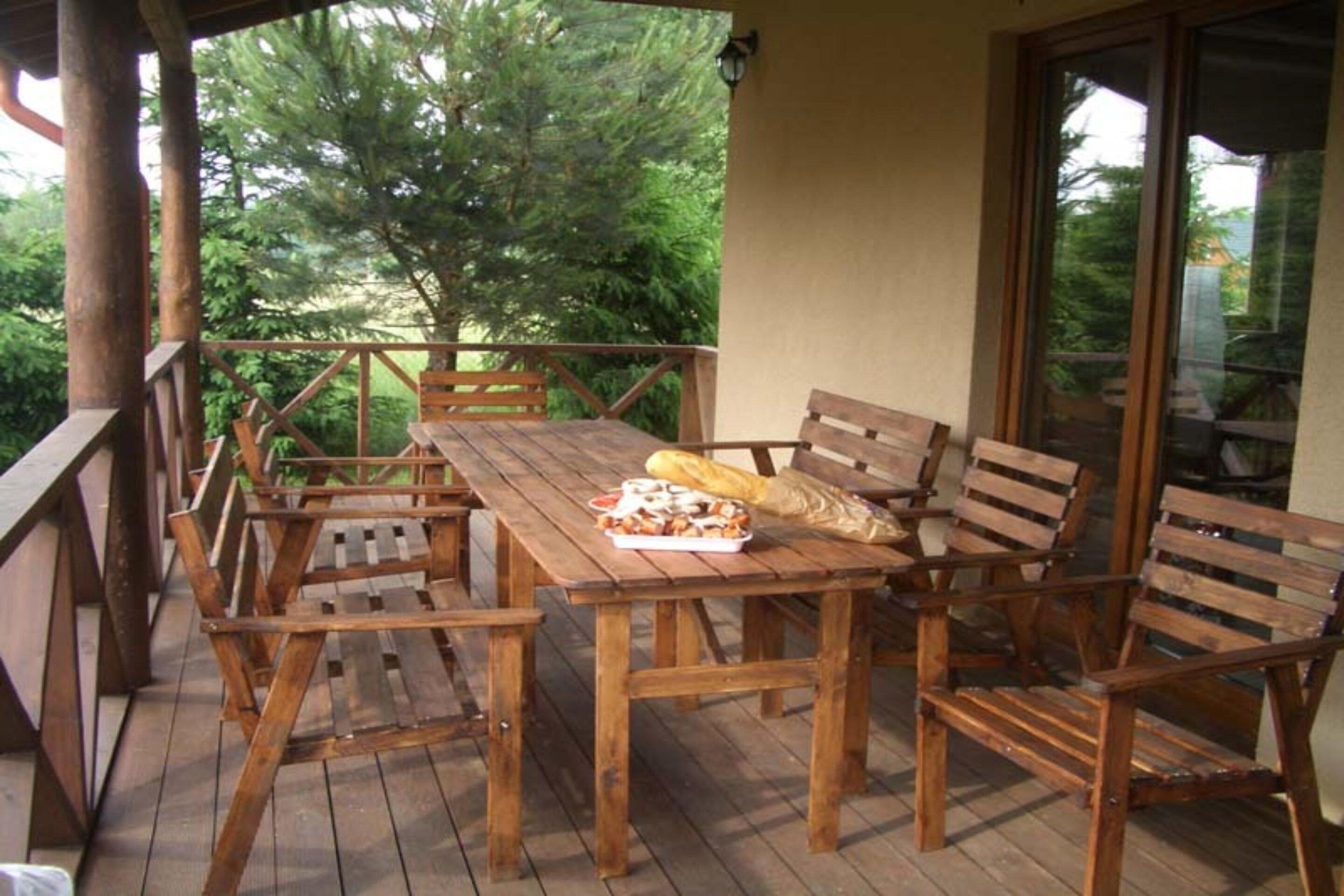 Una terraza de madera con una mesa, sillas, una bolsa de papas y un plato de comida.