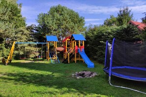 A playground with a slide, swings, and a trampoline. - Year-round Holiday Home With Fireplace, 3 Bedrooms (Choczewo)