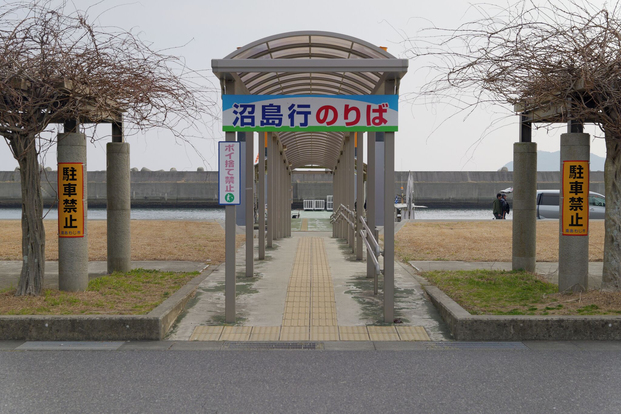 A covered walkway leading to a waterfront area with a sign indicating a parking stop.