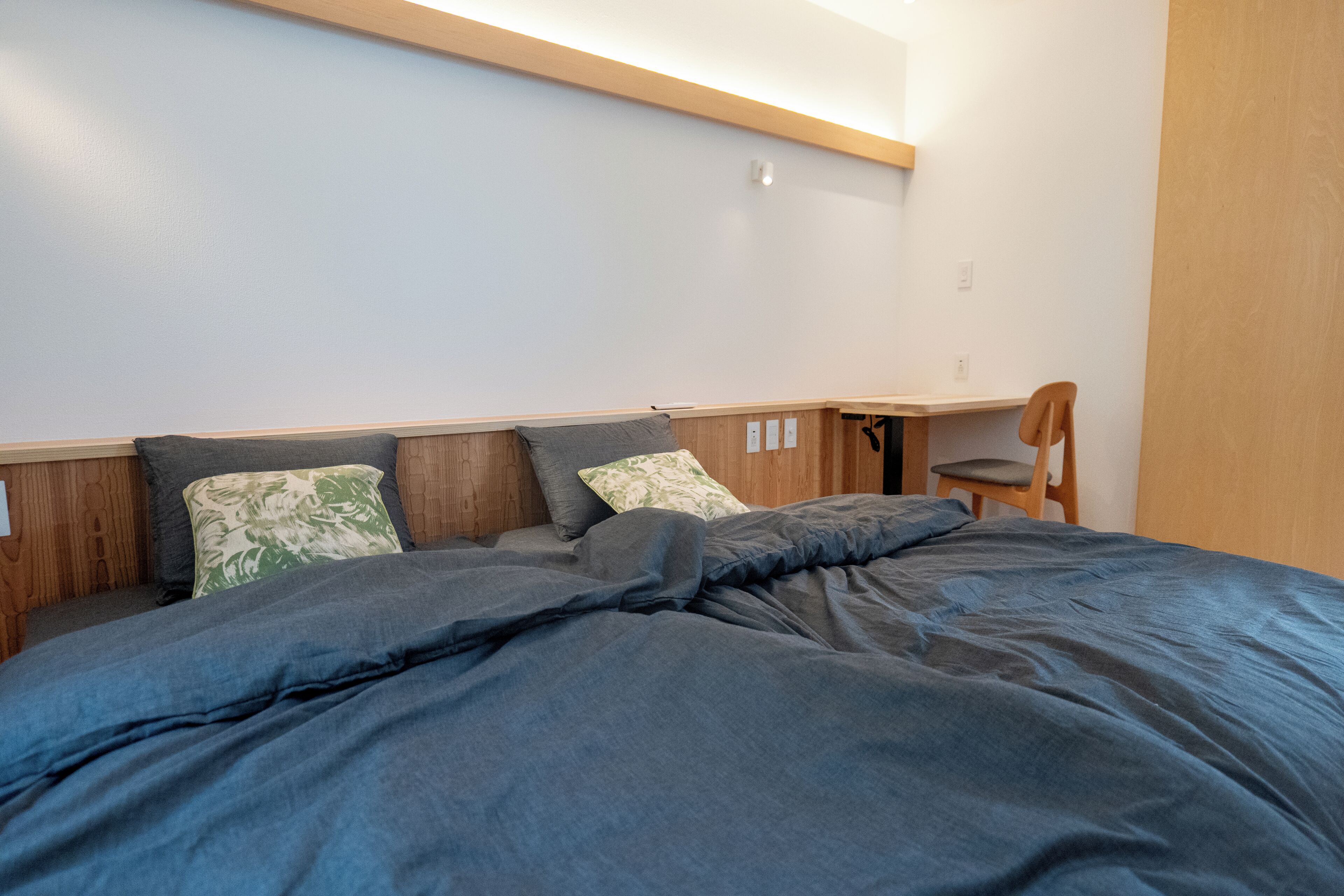 A bedroom with a bed, pillows, a chair, and a wooden headboard.