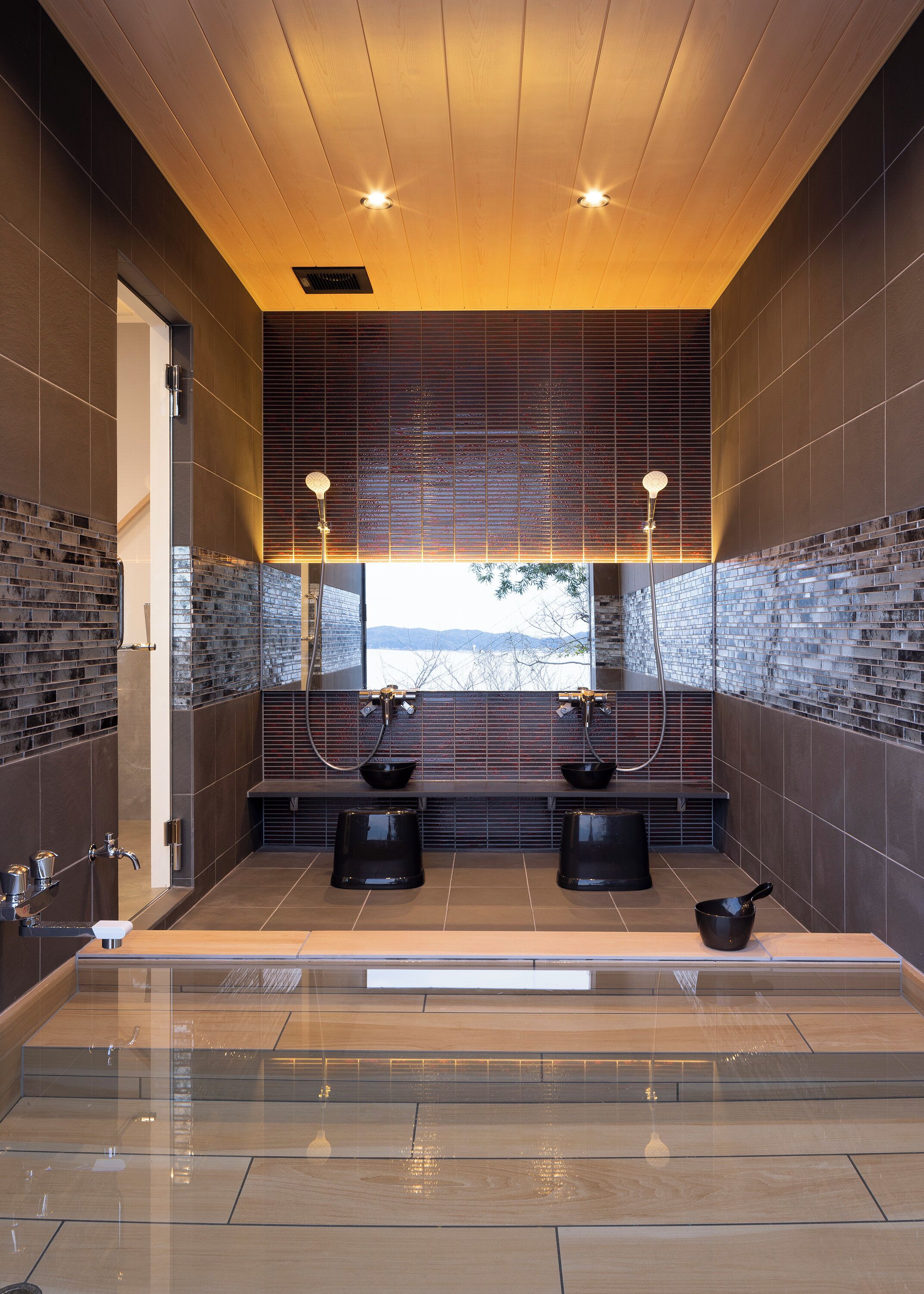 A modern bathroom with a wooden ceiling, two sinks with black basins, and a large mirror.
