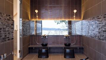 A modern bathroom with a wooden ceiling, two sinks with black basins, and a large mirror.