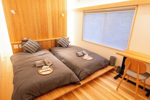 A room with two beds, a wooden desk, a chair, and a window with blinds. - WORKHOBBY Awajishima (Minamiawaji)