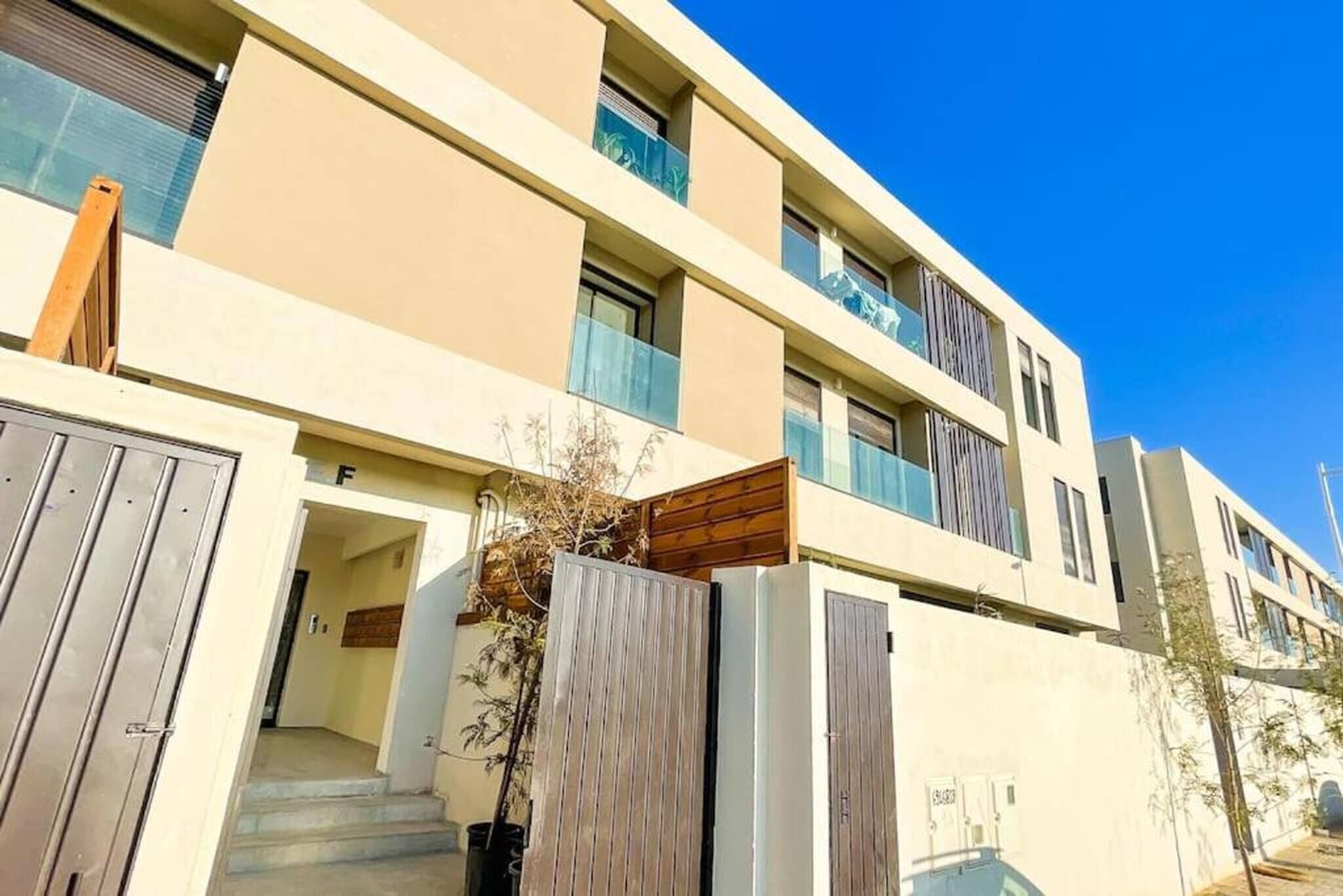 A modern multi-story building with a flat facade, large windows, and a visible entrance with steps.
