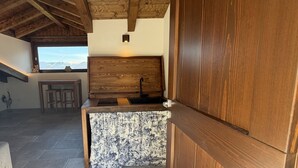 A rustic interior with a wooden ceiling, a sink, and a window with a mountain view. - Enchantment of the Lake app Palanzo Studio Apartment with Terrace A/C (Molina)