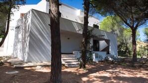 Un edificio moderno e bianco con una scalinata che conduce all'ingresso, circondato da alberi.