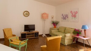 Un soggiorno con TV, divano, poltrone e opere d'arte appese al muro.