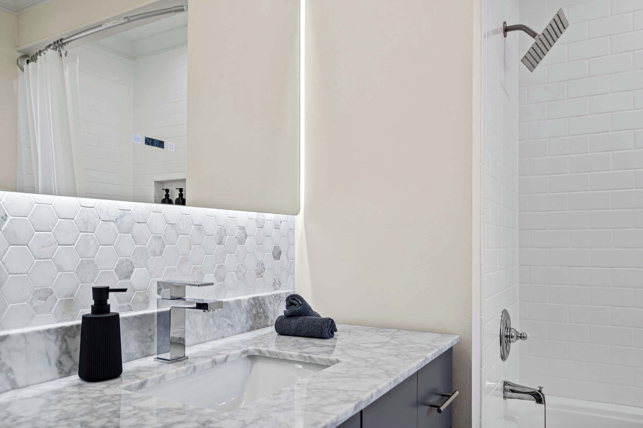 A bathroom with a white sink, a mirror, a towel, and a shower.