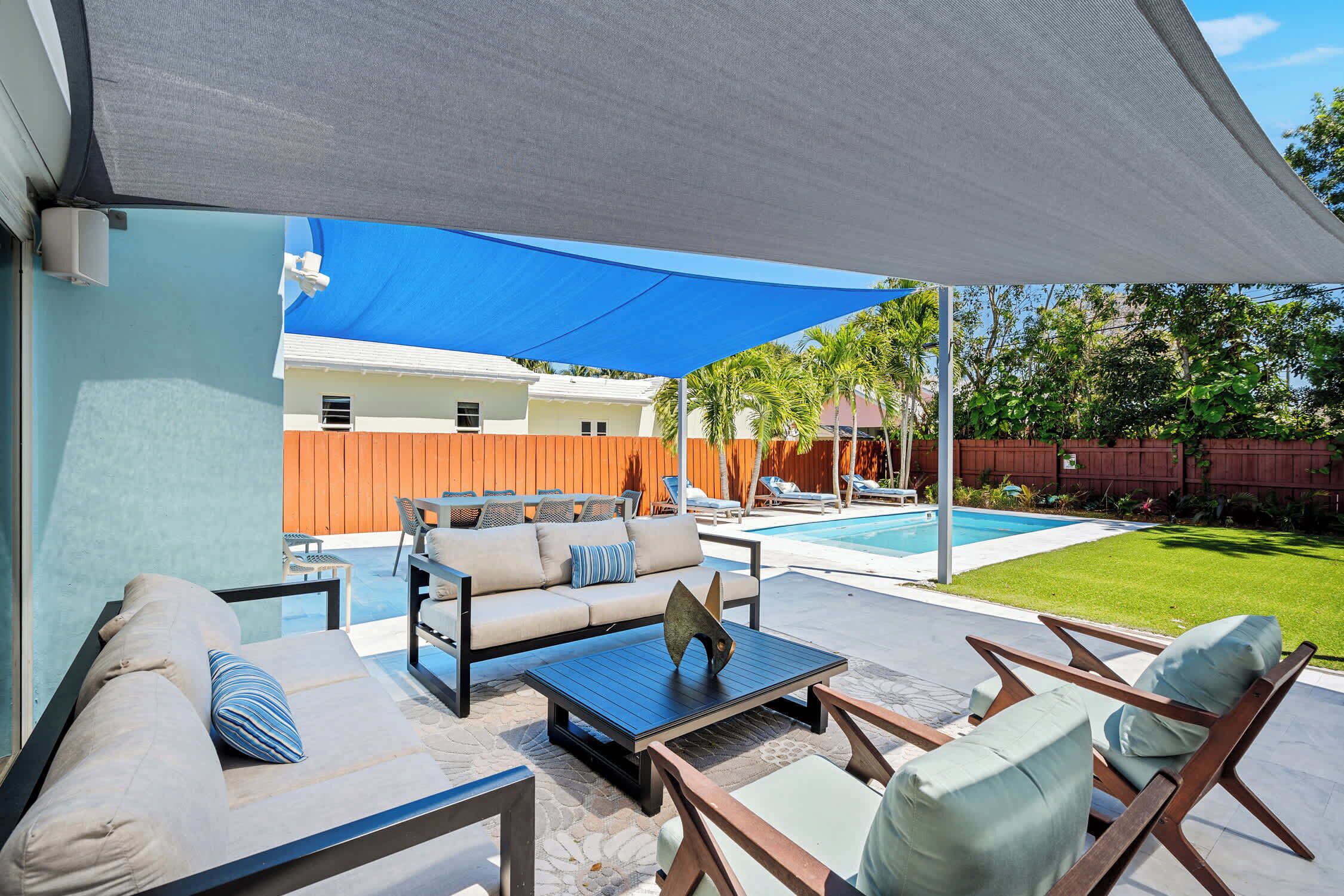 An outdoor patio with a sofa, chairs, and a pool.