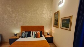 Ein Schlafzimmer mit einem großen Bett, zwei Nachttischen mit Lampen, einer Wandleuchte und zwei gerahmten Bildern.
