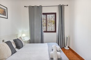 A bedroom with a bed, a nightstand, a lamp, a window with curtains, and a standing heater. - Family Retreat 5 Minutes’ Walk from D. Luís I Bridge (Vila Nova de Gaia)