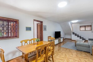 A dining area with a wooden table and chairs, a television, and a staircase leading to an upper level. - Family Retreat 5 Minutes’ Walk from D. Luís I Bridge (Vila Nova de Gaia)
