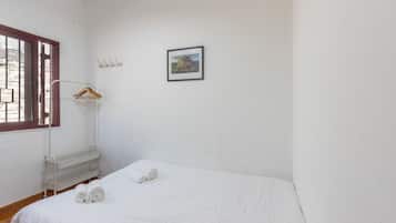 Una stanza semplice e pulita con un letto singolo, una finestra vista e un quadro appeso al muro.