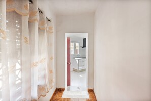A hallway leading to a kitchen with white cabinets and a red door. - Family Retreat 5 Minutes’ Walk from D. Luís I Bridge (Vila Nova de Gaia)