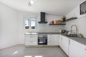 Ett modernt kök med vita skåp, en inbyggd ugn och ett fönster med utsikt över omgivningen.