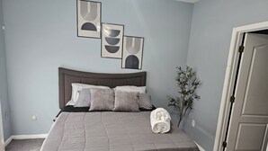 Un dormitori amb un llit, almoines, una manta i decoració a les parets.