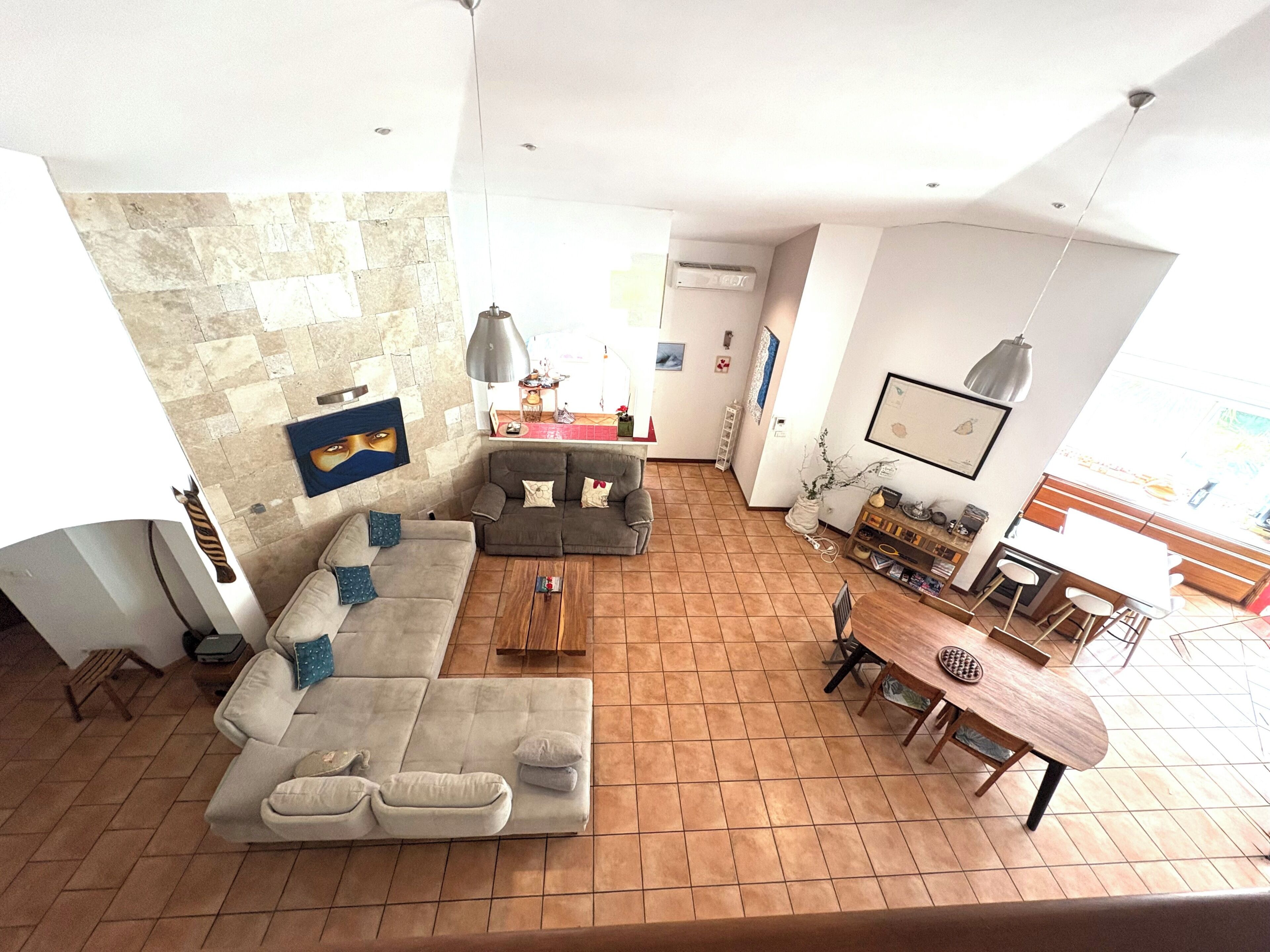 Amplia sala de estar con un sofá grande, una mesa de comedor y una zona de cocina.
