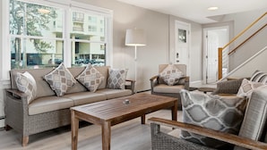 A living room with a sofa, armchairs, a coffee table, and a lamp. - Drift Cottage Steps to Beach (Old Orchard Beach)