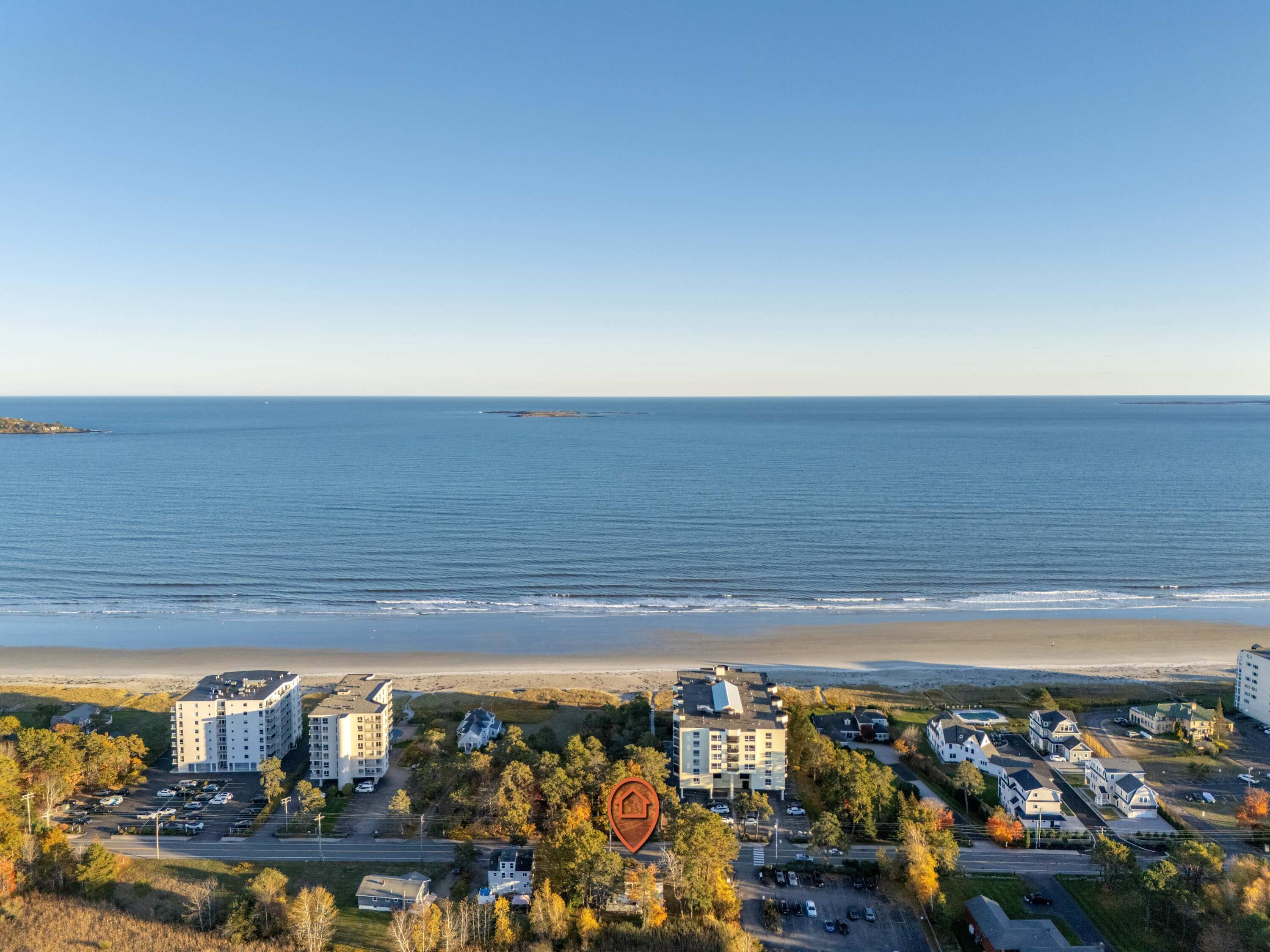 Un hôtel situé sur la côte, composé de plusieurs bâtiments, doté d’aires de stationnement et offrant une vue sur la plage.