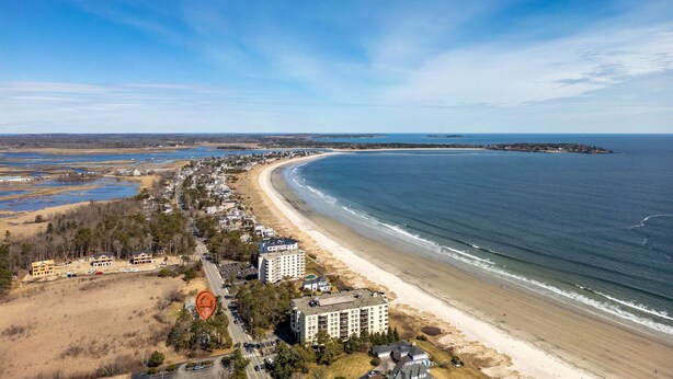 An aerial view of a coastal area with a beach, buildings, and a large body of water. - Drift Cottage Steps to Beach (Old Orchard Beach)