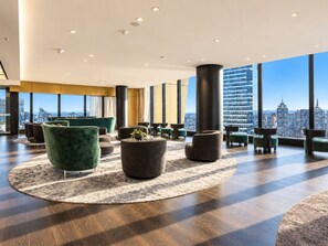 A modern lounge area with round tables, green chairs, and a city view. - Skyline Suites | Floor-to-Ceiling Views, Level 38 (Southbank)