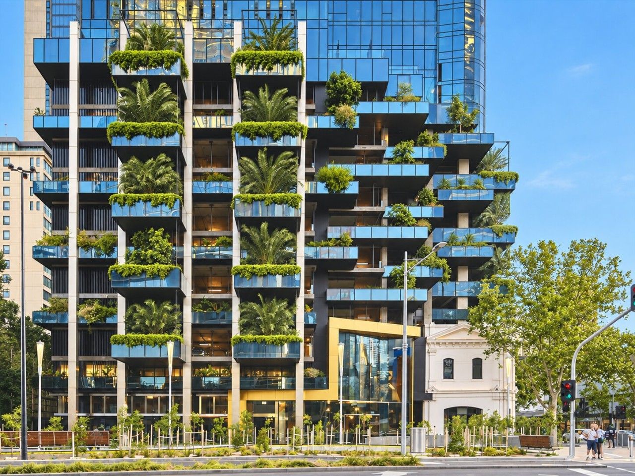 Um edifício moderno alto com várias varandas, algumas com vegetação.