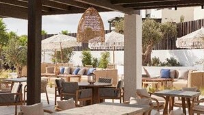 Un patio al aire libre con mobiliario de mimbre, mesas y sombrillas.