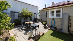 A patio with a table and chairs, a water heater, and a small garden.